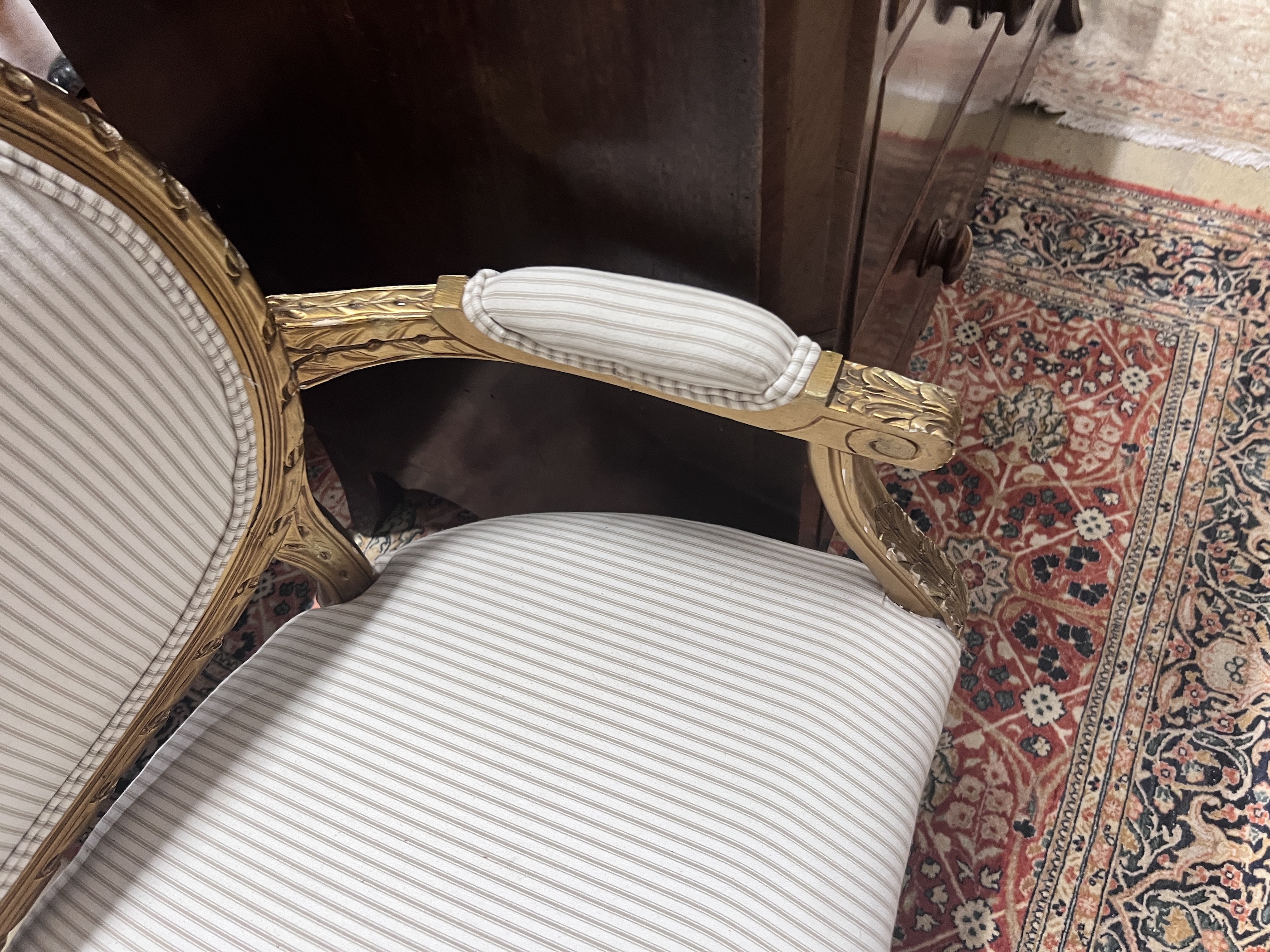 A French giltwood and composition settee, recently re-upholstered in a striped linen fabric, width 140cm, depth 60cm, height 92cm